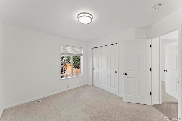 unfurnished bedroom with a closet and light colored carpet