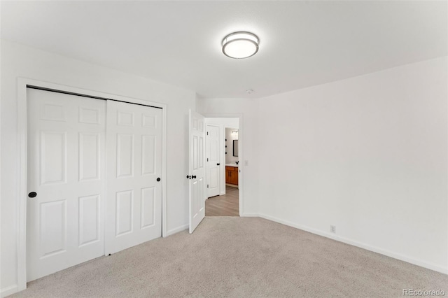 unfurnished bedroom with light carpet and a closet