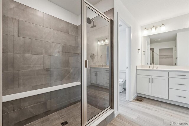 bathroom featuring a shower stall, vanity, toilet, and wood finished floors