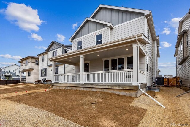 view of front facade featuring board and batten siding, covered porch, and central AC