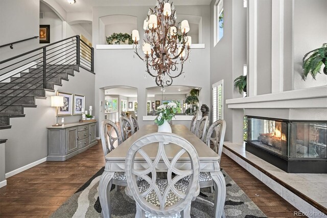 6242 Shea Pl, Highlands Ranch, CO 80130 - dining area featuring a multi sided fireplace, stairs, wood finished floors, a towering ceiling, and arched walkways