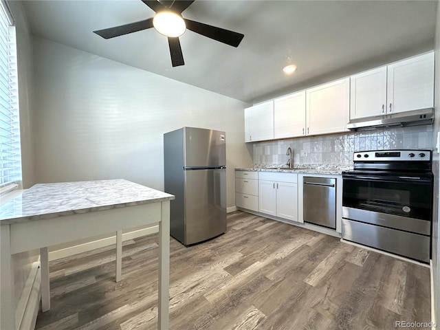 kitchen featuring hardwood / wood-style floors, tasteful backsplash, white cabinetry, stainless steel appliances, and light stone countertops