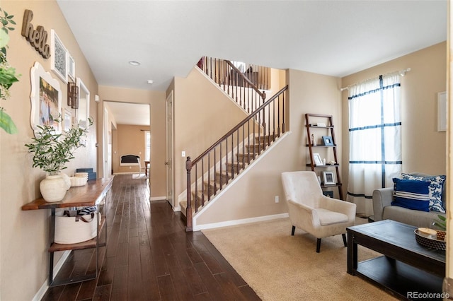 living area featuring stairway, baseboards, dark wood-type flooring, and plenty of natural light