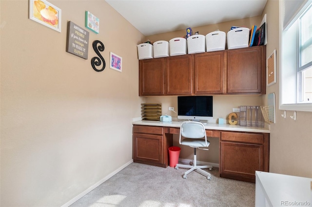 office with built in study area, light colored carpet, and baseboards