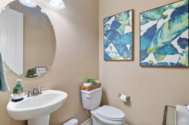 half bath featuring a sink, toilet, and baseboards