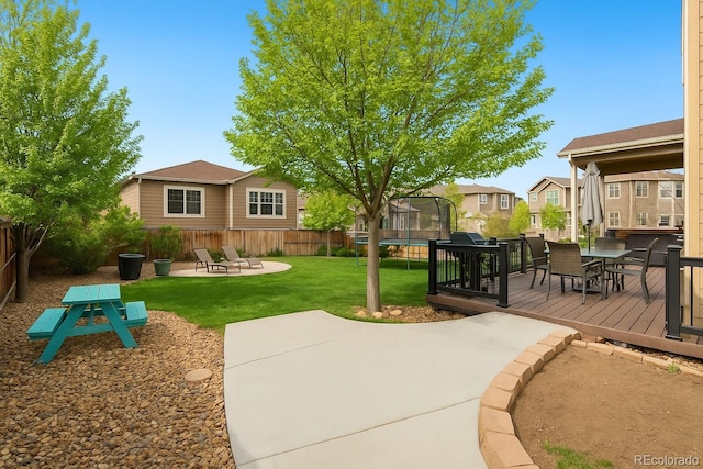 view of property's community with a trampoline, a patio, a wooden deck, outdoor dining area, and a residential view