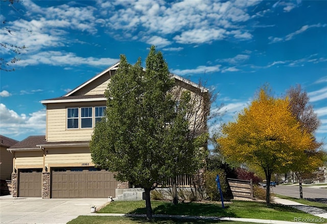view of front of property featuring fence, an attached garage, concrete driveway, and stone siding