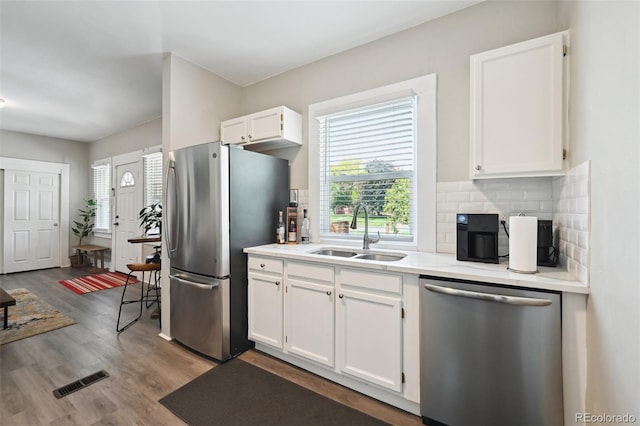 1456 Syracuse St, Denver, CO 80220 - kitchen featuring stainless steel appliances, a sink, wood finished floors, decorative backsplash, and white cabinetry
