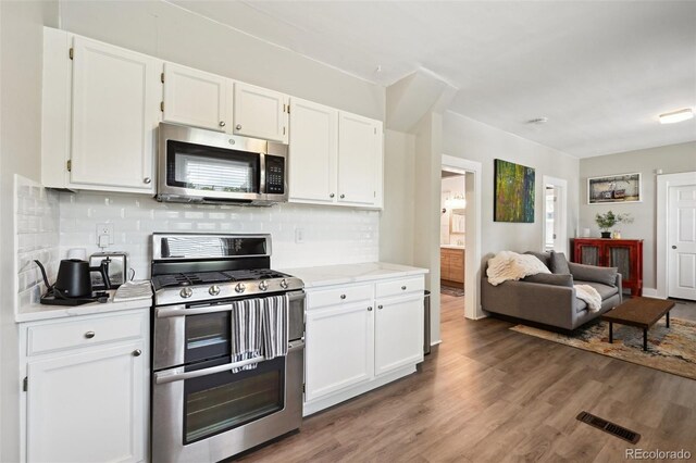 1456 Syracuse St, Denver, CO 80220 - kitchen with stainless steel appliances, white cabinetry, open floor plan, and tasteful backsplash