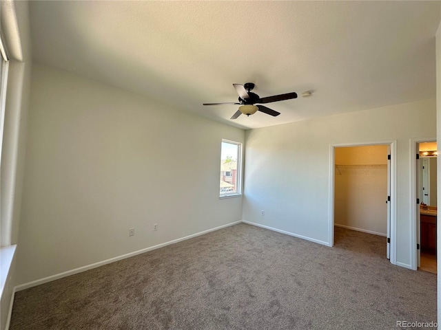 unfurnished bedroom featuring a spacious closet, carpet floors, baseboards, and a closet