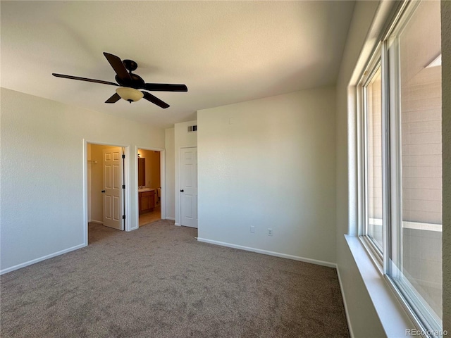unfurnished bedroom with carpet flooring, baseboards, ensuite bath, and ceiling fan