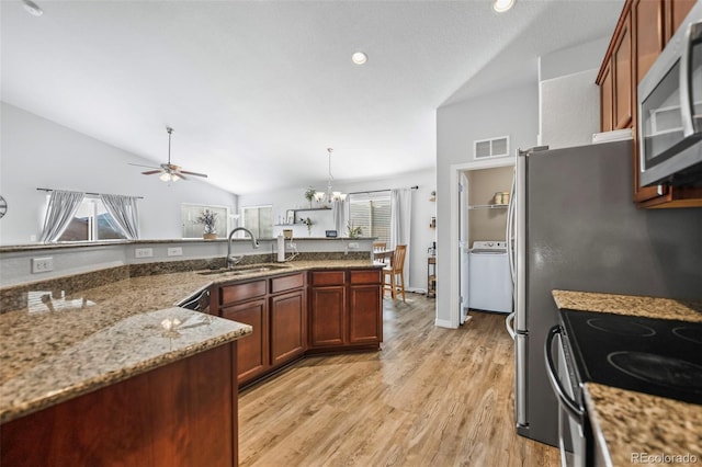 kitchen with light wood-type flooring, vaulted ceiling, sink, stainless steel appliances, and hanging light fixtures