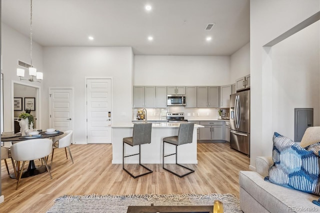 487 Interlocken Blvd Unit 104, Broomfield, CO 80021 - kitchen with gray cabinetry, appliances with stainless steel finishes, a towering ceiling, light countertops, and a kitchen breakfast bar