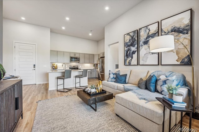 487 Interlocken Blvd Unit 104, Broomfield, CO 80021 - living area featuring a towering ceiling, light wood finished floors, recessed lighting, and baseboards