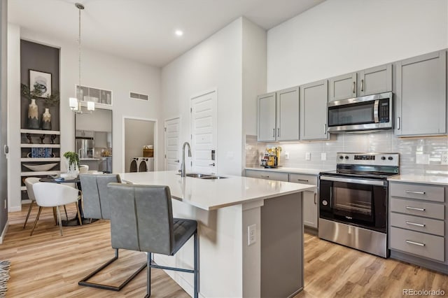 487 Interlocken Blvd Unit 104, Broomfield, CO 80021 - kitchen featuring appliances with stainless steel finishes, a sink, gray cabinets, a towering ceiling, and light wood-style floors