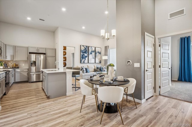487 Interlocken Blvd Unit 104, Broomfield, CO 80021 - dining room featuring a towering ceiling, light wood-style flooring, a chandelier, recessed lighting, and baseboards