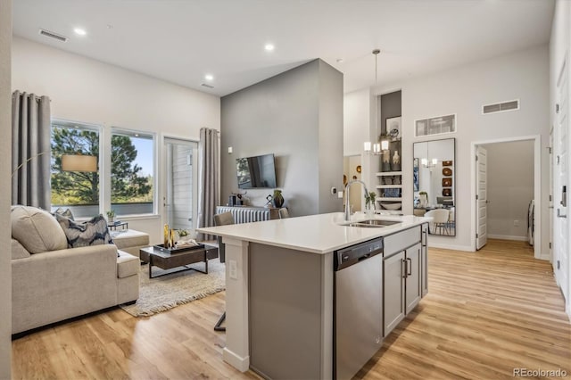 487 Interlocken Blvd Unit 104, Broomfield, CO 80021 - kitchen featuring stainless steel dishwasher, a sink, open floor plan, a high ceiling, and light wood-style flooring