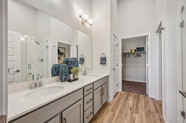 487 Interlocken Blvd Unit 104, Broomfield, CO 80021 - full bathroom with a spacious closet, a stall shower, double vanity, and wood finished floors