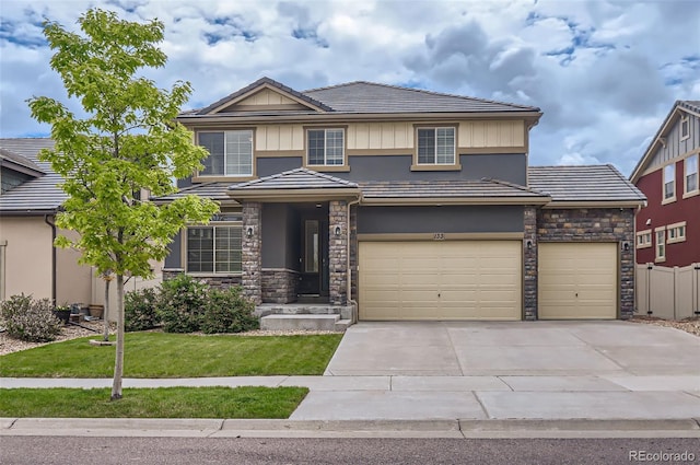 133 Poppy View Ln, Erie, CO 80516 - view of front facade featuring stone siding, driveway, a tile roof, an attached garage, and stucco siding