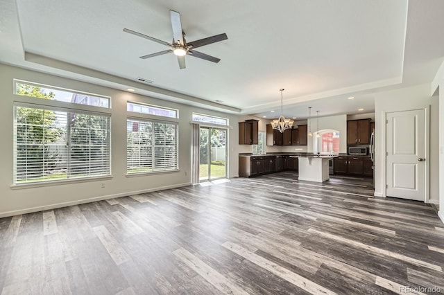 133 Poppy View Ln, Erie, CO 80516 - unfurnished living room with a raised ceiling, a chandelier, dark wood-style floors, plenty of natural light, and recessed lighting