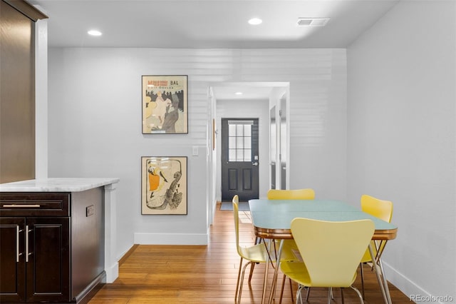 dining area featuring light wood finished floors, baseboards, and recessed lighting