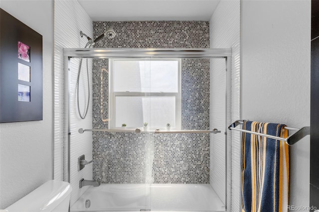 bathroom with toilet and combined bath / shower with glass door