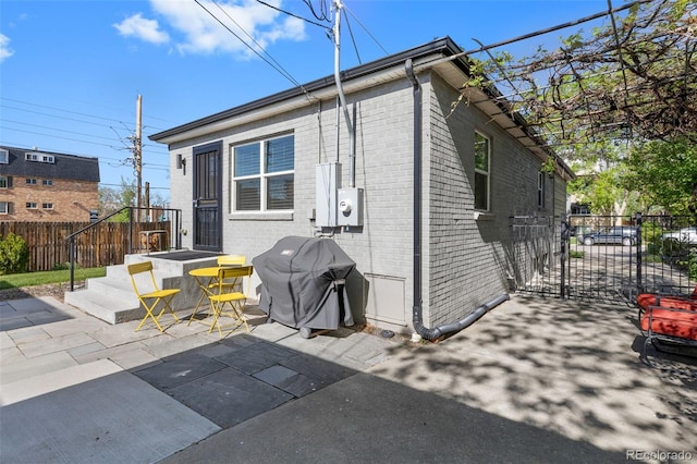 rear view of property with brick siding, fence, and a patio area