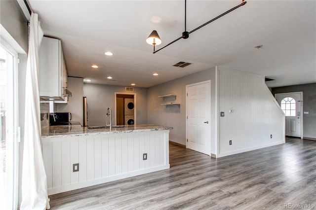 3607 Dinosaur St, Castle Rock, CO 80109 - kitchen with a sink, stacked washer / drying machine, a peninsula, wood finished floors, and light stone countertops