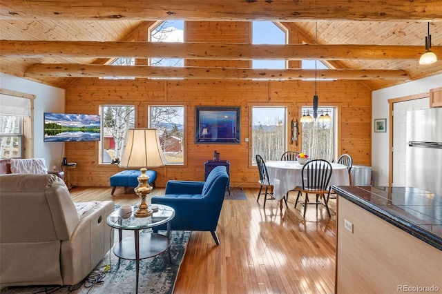 living room featuring a wealth of natural light, light hardwood / wood-style flooring, and vaulted ceiling with beams