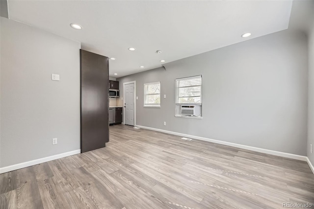 unfurnished living room featuring baseboards, light wood-style floors, recessed lighting, and cooling unit