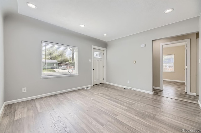 unfurnished living room with healthy amount of natural light, baseboards, recessed lighting, and light wood-type flooring