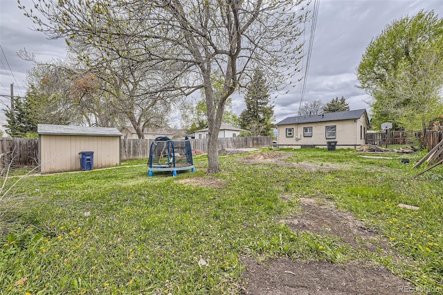 view of yard featuring a trampoline, an outdoor structure, and a storage shed