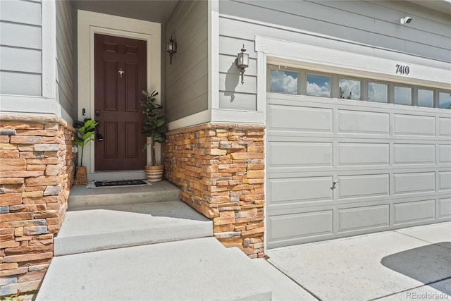 property entrance featuring stone siding and a garage
