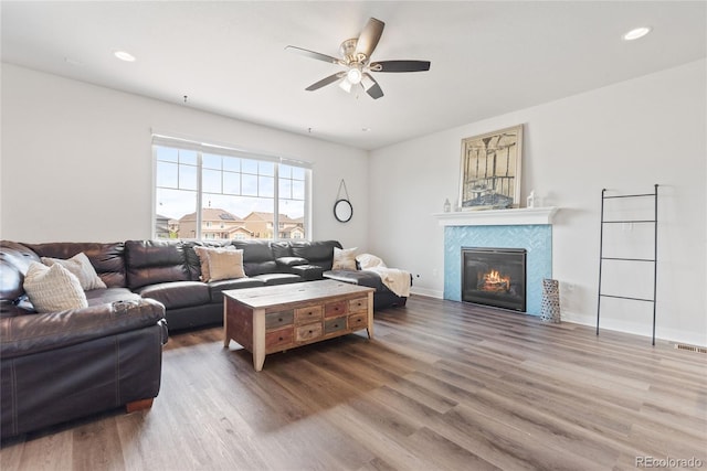 living area with ceiling fan, a fireplace, wood finished floors, recessed lighting, and baseboards