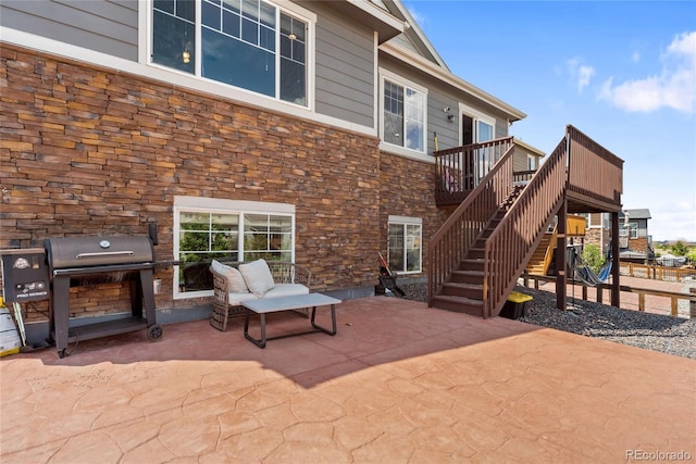 rear view of house with stone siding, a patio, stairway, and a wooden deck