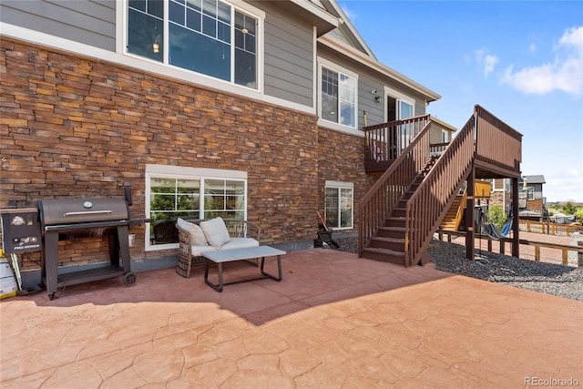 rear view of house with stone siding, a patio area, stairs, and a deck