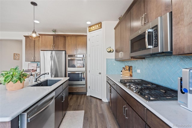 kitchen featuring appliances with stainless steel finishes, a sink, light countertops, dark wood-style floors, and recessed lighting