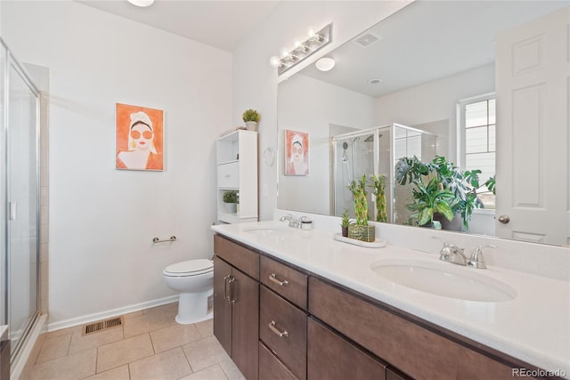 bathroom with a shower stall, toilet, double vanity, tile patterned flooring, and baseboards