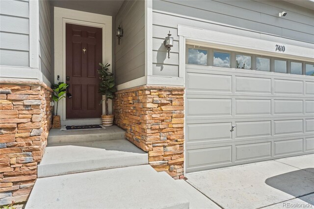 7410 S Old Hammer Way, Aurora, CO 80016 - doorway to property featuring stone siding and a garage