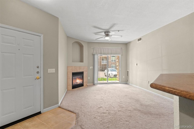 7440 S Blackhawk St Unit 104, Englewood, CO 80112 - unfurnished living room featuring ceiling fan, carpet floors, a tile fireplace, and a textured ceiling