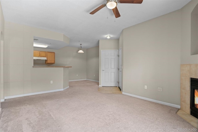 7440 S Blackhawk St Unit 104, Englewood, CO 80112 - unfurnished living room featuring a tiled fireplace, light colored carpet, and a ceiling fan