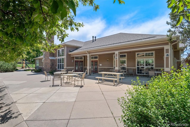 7440 S Blackhawk St Unit 104, Englewood, CO 80112 - back of house with french doors, a patio, roof with shingles, and stone siding