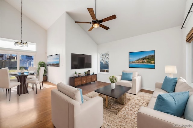 living room featuring high vaulted ceiling, light hardwood / wood-style floors, and ceiling fan