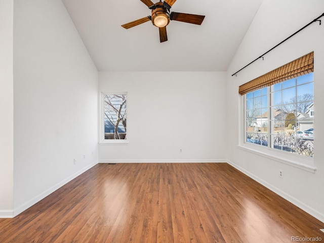 empty room featuring lofted ceiling, hardwood / wood-style floors, a healthy amount of sunlight, and ceiling fan