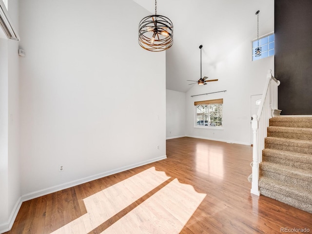 unfurnished living room with a towering ceiling, wood-type flooring, and ceiling fan