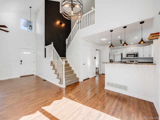 interior space featuring a high ceiling, wood-type flooring, and an inviting chandelier