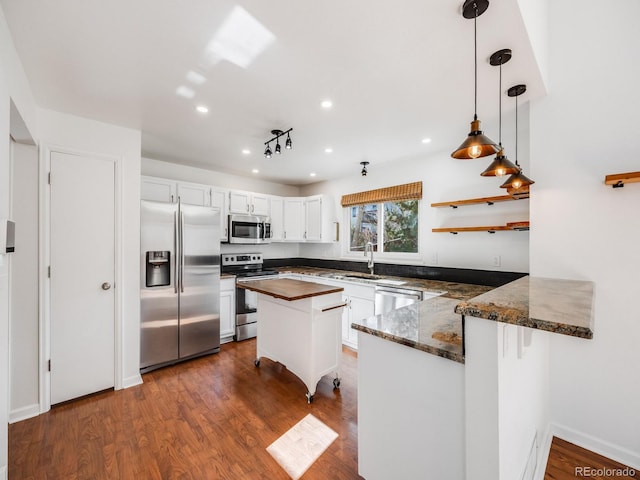 kitchen with decorative light fixtures, sink, white cabinets, kitchen peninsula, and stainless steel appliances