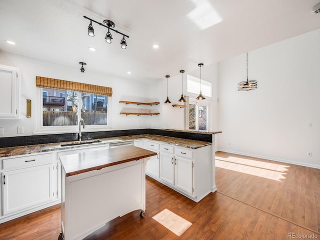 kitchen featuring white cabinetry, sink, hanging light fixtures, and a center island