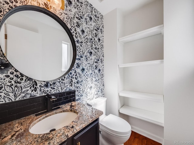 bathroom featuring vanity, wood-type flooring, backsplash, and toilet