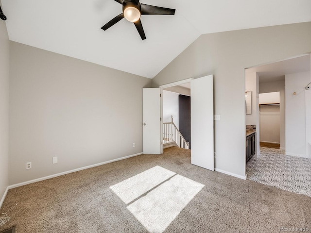 unfurnished bedroom with ceiling fan, a spacious closet, vaulted ceiling, and light carpet